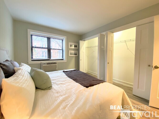 A bedroom with a bed, pillows, and a window.