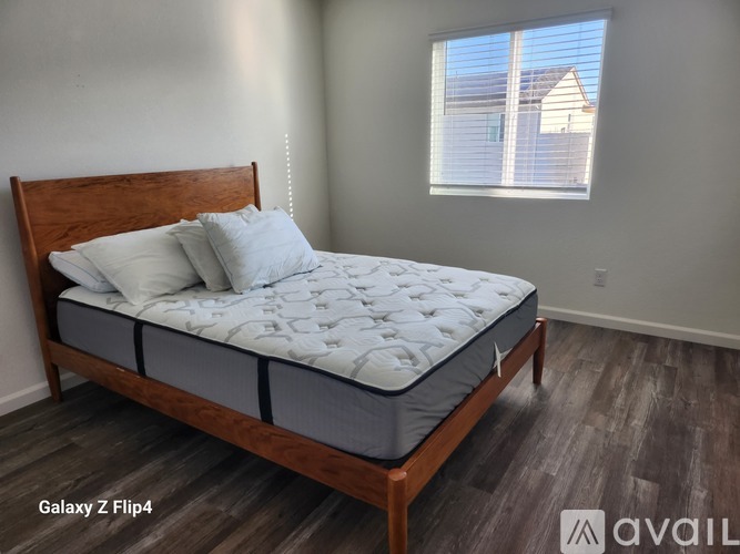 A bed with a wooden headboard and footboard with a white mattress and two pillows in a room with a window.