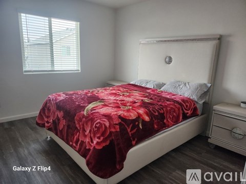 A bedroom with a bed covered in a red floral bedspread.