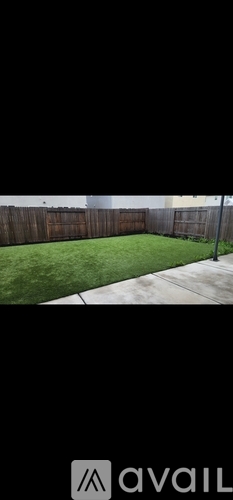 A backyard with a wooden fence and a green lawn.