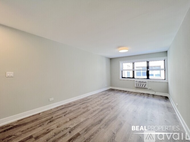 A spacious room with wooden flooring and a window overlooking a cityscape.