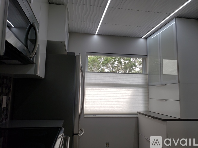A kitchen with a black refrigerator and white cabinets.
