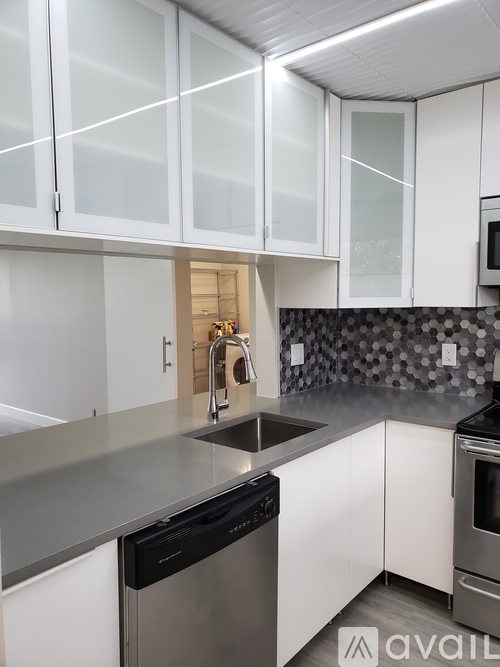 A kitchen with white cabinets and a black dishwasher.
