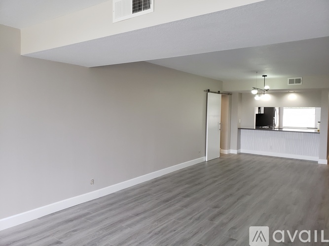 A spacious room with wooden flooring and a flat screen TV in the corner.