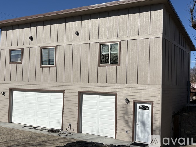 A two-car garage with a brown siding and a white door is available for rent.