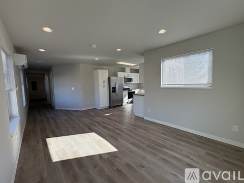 A spacious living room with a kitchen in the background and a rug on the floor.