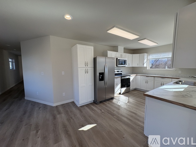 A kitchen with white cabinets and a wooden floor.