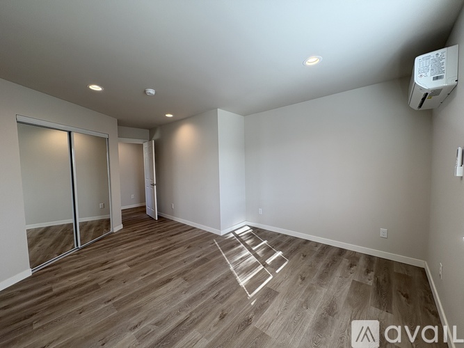 A spacious room with wooden flooring and a staircase leading to another level.