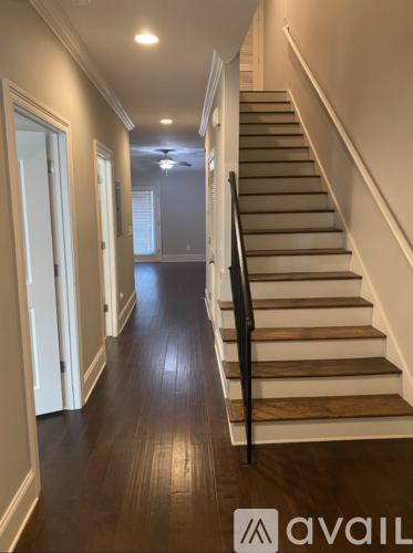 A staircase with a black handrail and wooden steps.