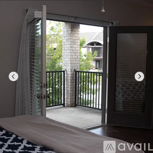 A bedroom with a bed and a view of a balcony through a glass door.