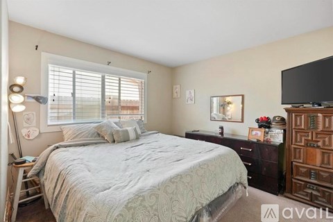 A bedroom with a bed, dresser, and window with blinds.