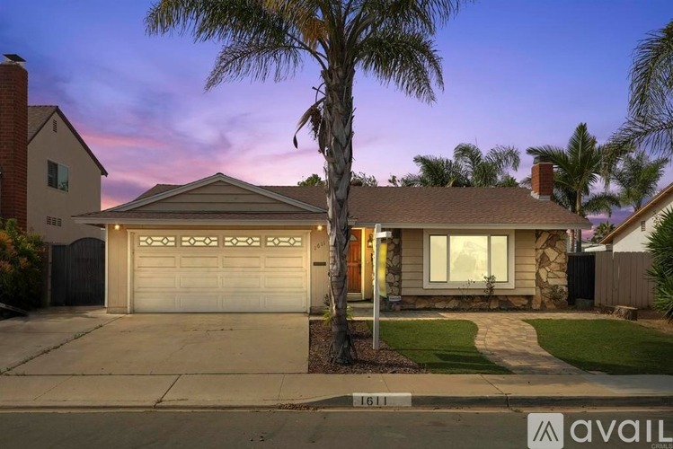 A house with a garage and a tree in front of it.