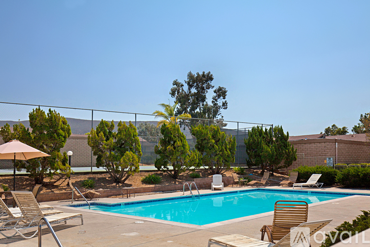 A pool surrounded by trees and chairs.