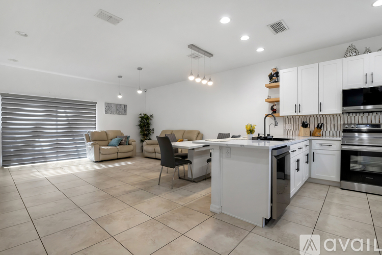 A modern kitchen with white appliances and a dining table with chairs.
