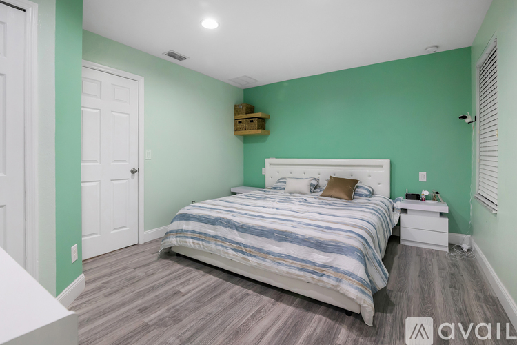 A bedroom with a bed, nightstand, and a wooden crate on the wall.