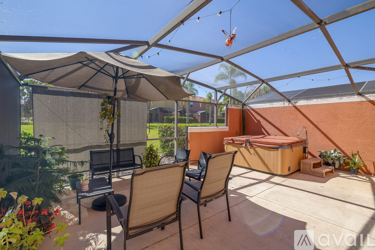 A patio with a table, chairs, and a hot tub under a canopy.