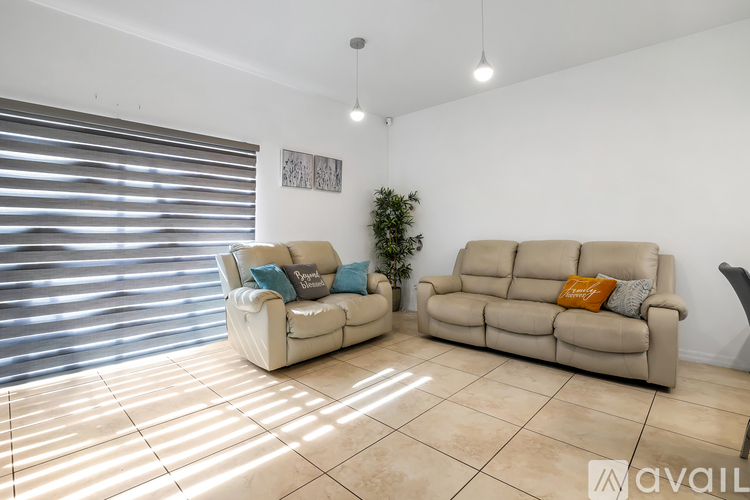 Two tan couches in a living room with a plant and picture on the wall.
