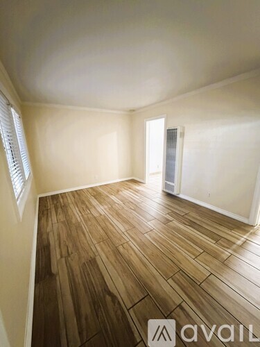 A room with wooden flooring and a window with blinds.