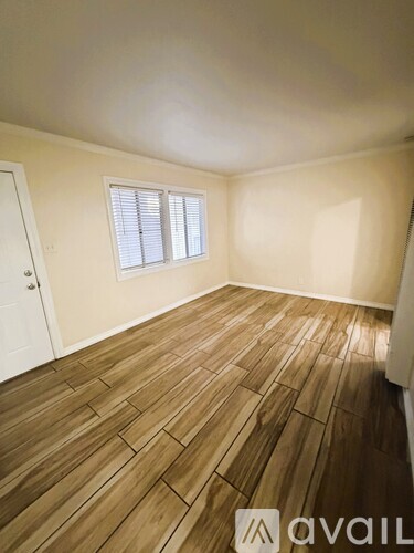 A room with wooden flooring and a window with blinds.