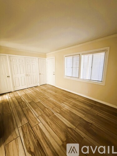 A room with wooden flooring and white walls.