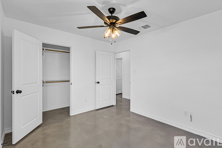 A room with a ceiling fan and three doors.