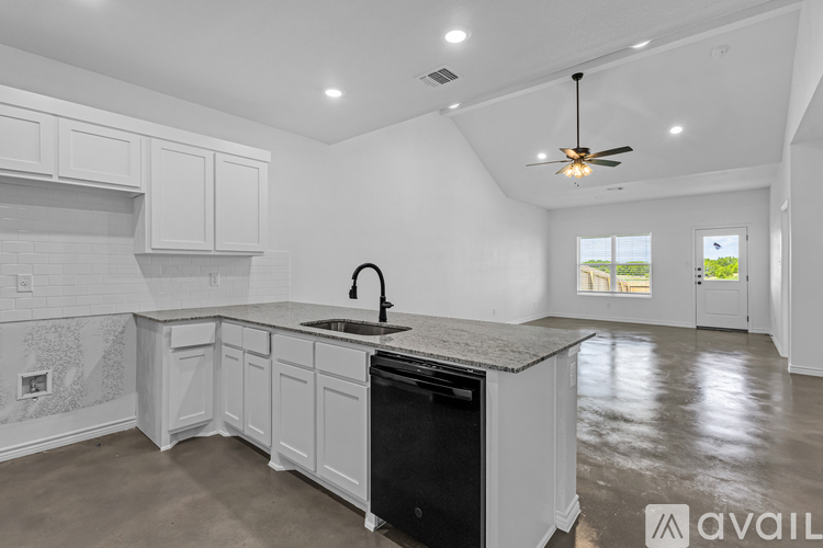 A modern kitchen with white cabinets and a black dishwasher.