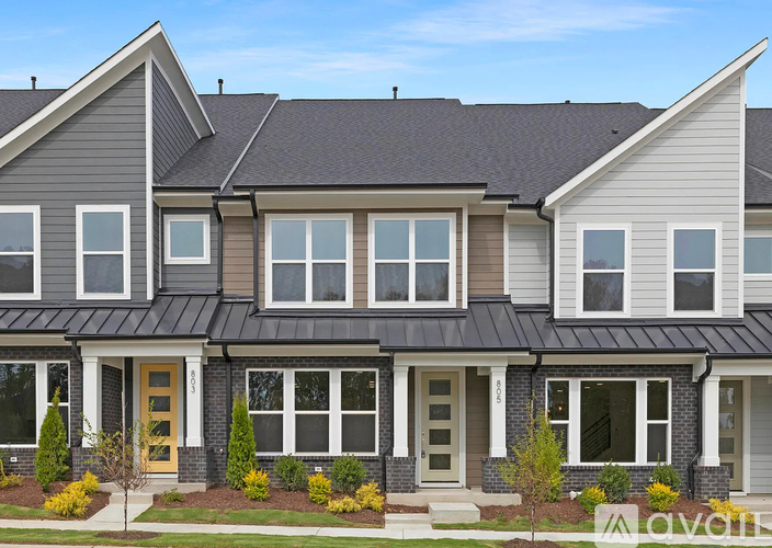 A modern two-story house with a grey exterior and a yellow front door.