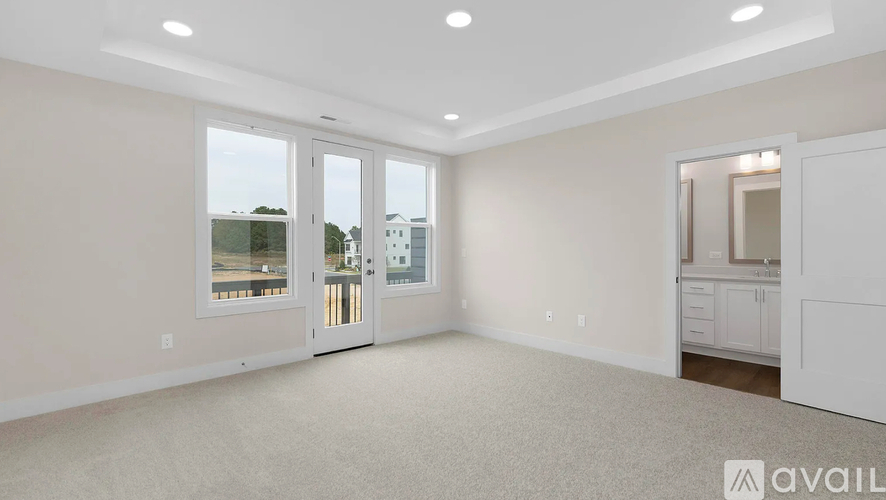 A spacious room with a carpeted floor and a large window overlooking a street.