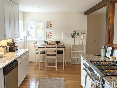 A kitchen with white cabinets and a wooden floor.