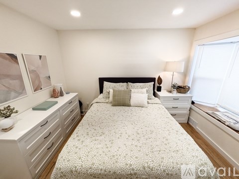 A bedroom with a bed, nightstand, and a dresser with a mirror.