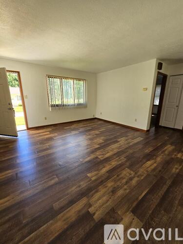 A room with wooden flooring and a window with blinds.