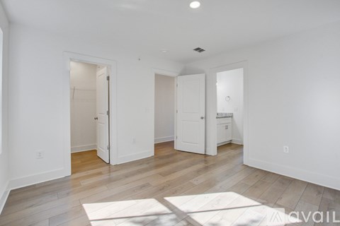 A spacious room with white walls and wooden flooring, featuring a large open doorway and a white mat on the floor.