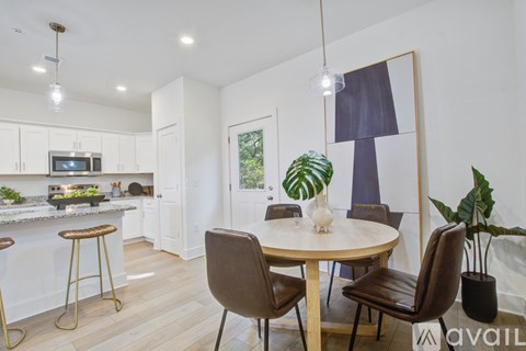 A kitchen with a table and chairs in the foreground and a framed picture on the wall.