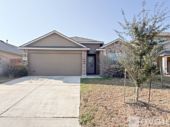 A house with a brown garage door is surrounded by other houses.