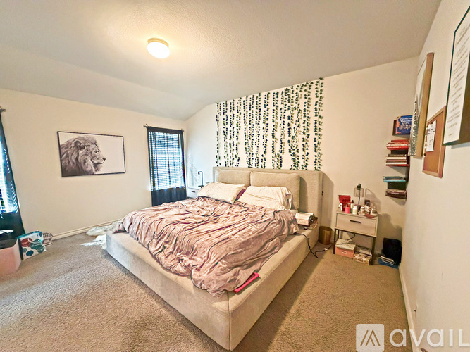 A bedroom with a bed, nightstand, and a picture of a lion on the wall.