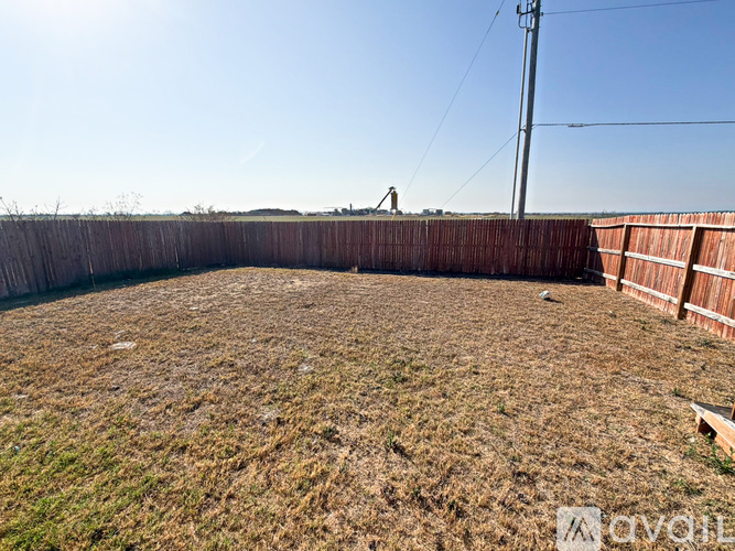 A backyard with a wooden fence and a grassy area.