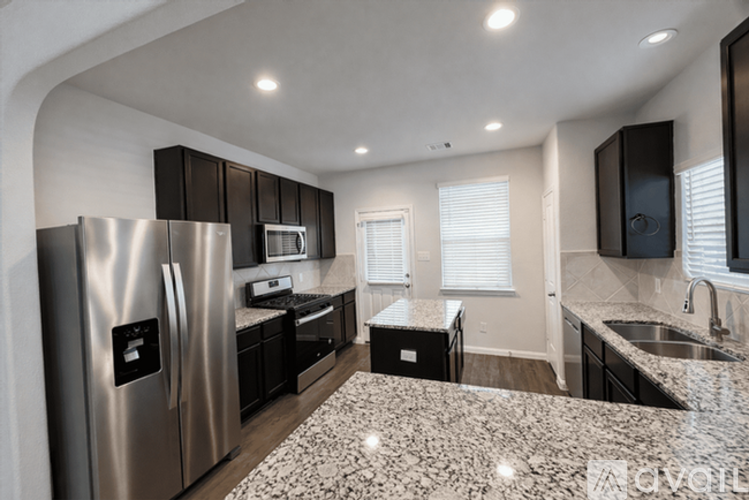 A modern kitchen with a granite countertop and stainless steel appliances.