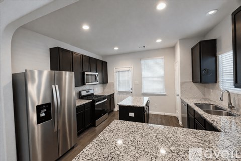A modern kitchen with a granite countertop and stainless steel appliances.