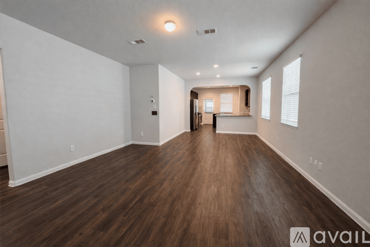 A spacious room with wooden flooring and white walls.
