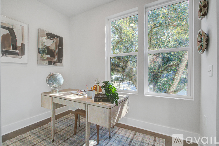 A room with a desk and a window showing trees outside.