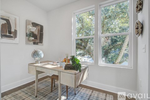 A room with a desk and a window showing trees outside.