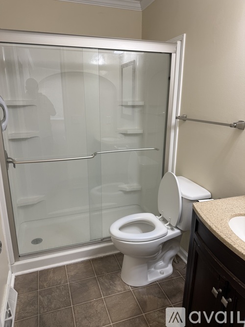 A white toilet with a glass shower door in a bathroom.