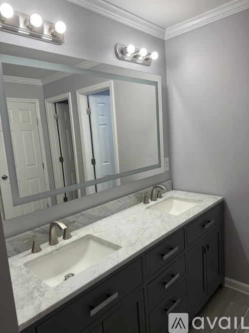 A bathroom with a sink, mirror, and lights.