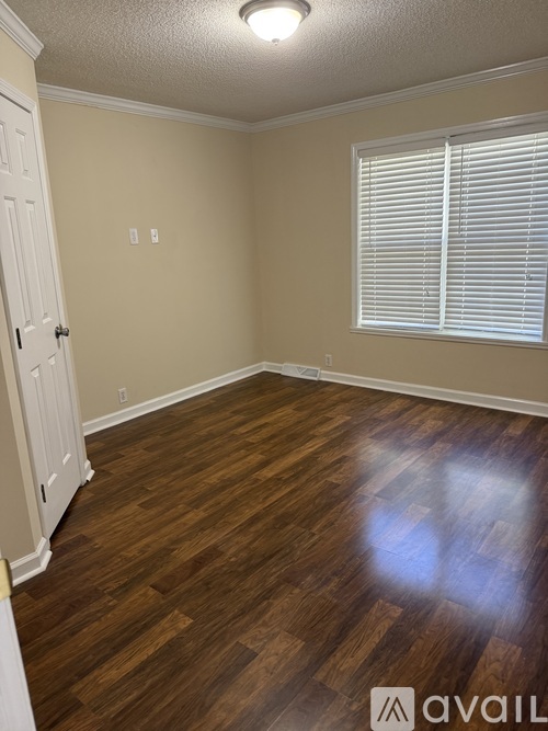 A room with wooden flooring and a window with blinds.