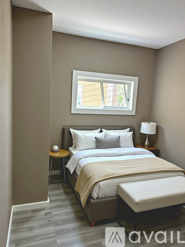 A bedroom with a large bed and a small table with a lamp.