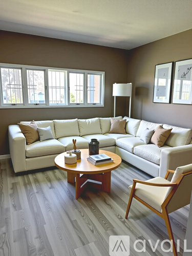 A living room with a white couch, wooden coffee table, and a chair.