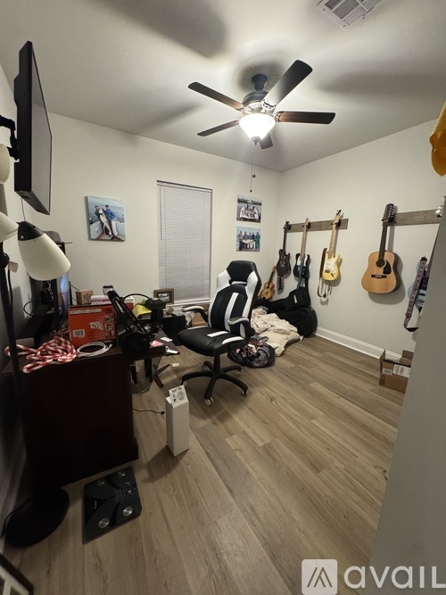 A room with a ceiling fan and guitars hanging on the wall.