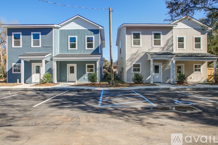 Two houses with blue and white exterior are situated next to each other with a parking lot in front.