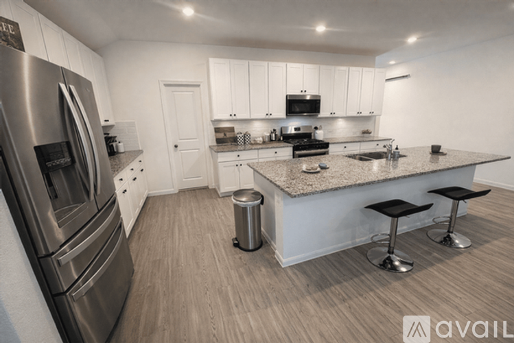 A modern kitchen with a stainless steel refrigerator and a granite countertop.