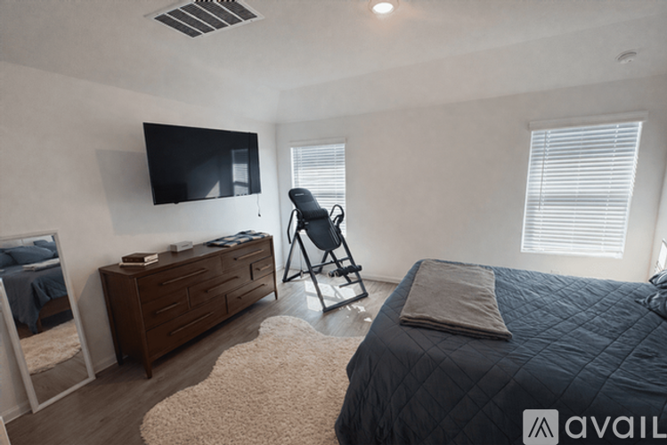 A bedroom with a bed, a chair, and a television mounted on the wall.
